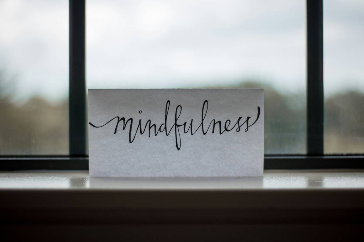 Person smiling quietly while holding phone showing buddhify app screen with 'Meditate Anytime' overlay text